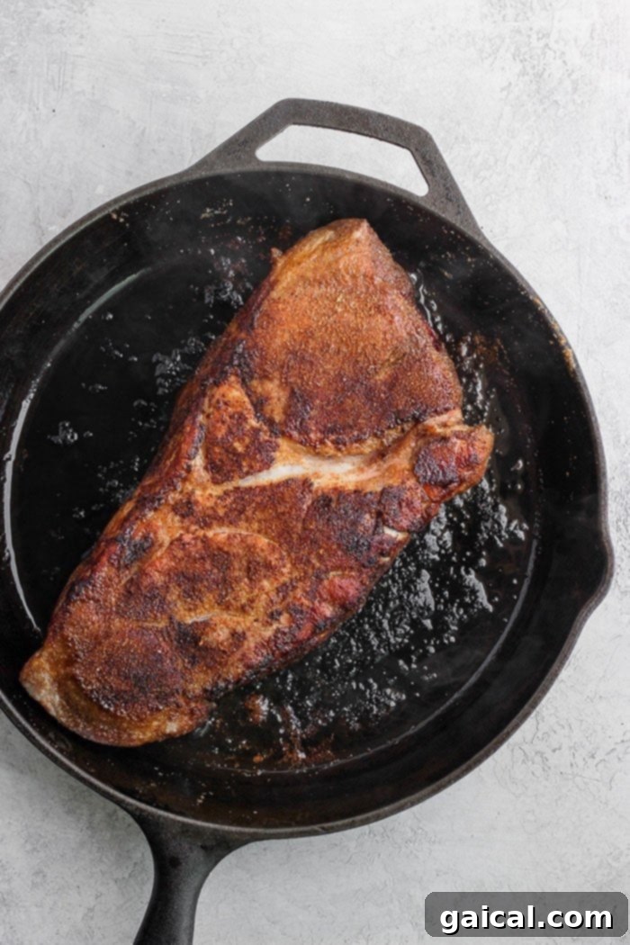Seasoned Pork in Cast Iron Skillet A perfectly dry-rubbed pork roast resting in a cast iron skillet, ready to be cooked to perfection.