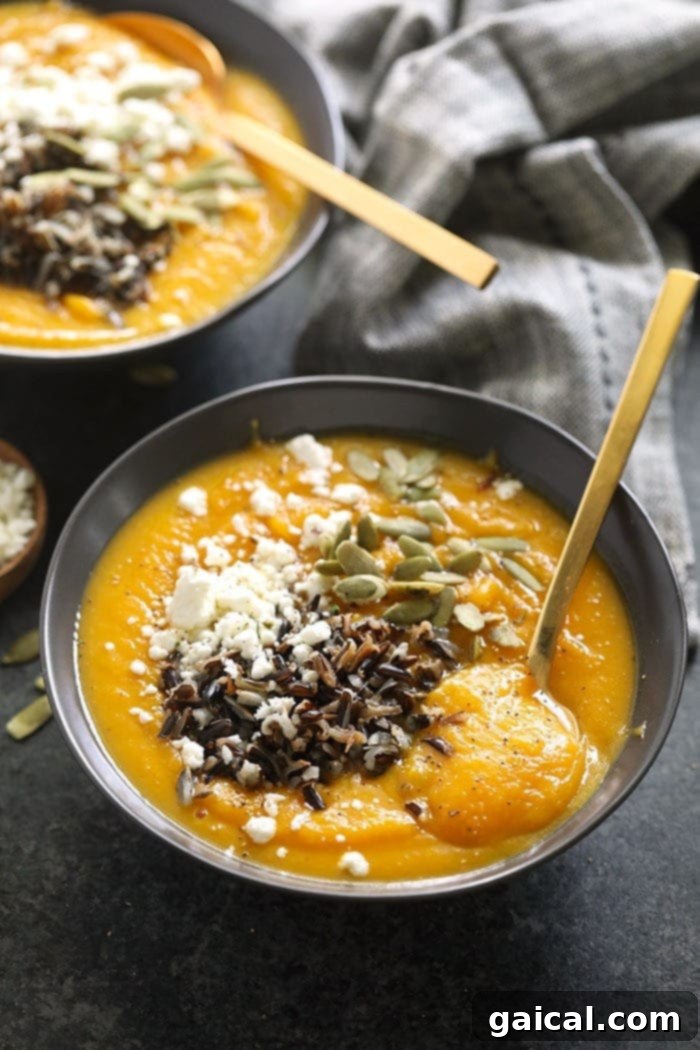 Instant Pot Butternut Squash Soup: A Quick, Creamy, and Healthy Vegan Delight A beautifully presented bowl of creamy Instant Pot Butternut Squash Soup, artfully topped with fluffy wild rice, crumbled goat cheese, and fresh green herbs, ready to be savored.
