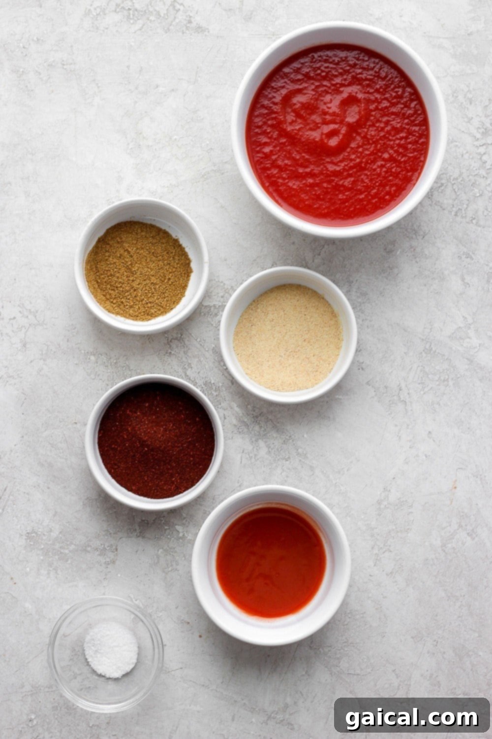 Ingredients for Homemade Enchilada Sauce laid out, including tomato sauce, chili powder, cumin, garlic powder, and hot sauce.