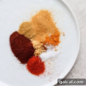 Fragrant One-Pan Moroccan Chicken 2 A vibrant array of ground spices arranged on a rustic plate, ready for a Moroccan dish.