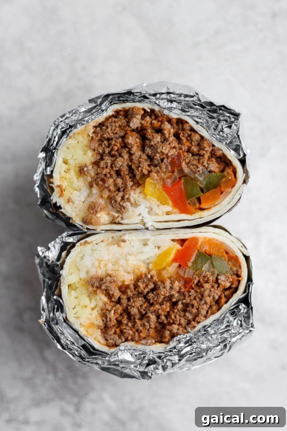 Batch Freezer Burritos 6 Several homemade burritos wrapped in tin foil, stacked in a freezer-safe container, ready for long-term storage.