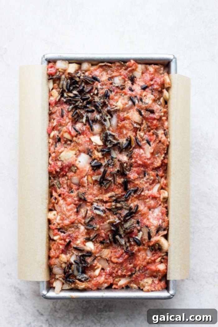 Unbaked Wild Rice Meatloaf mixture neatly pressed into a standard loaf pan, ready to be placed in the oven for baking.