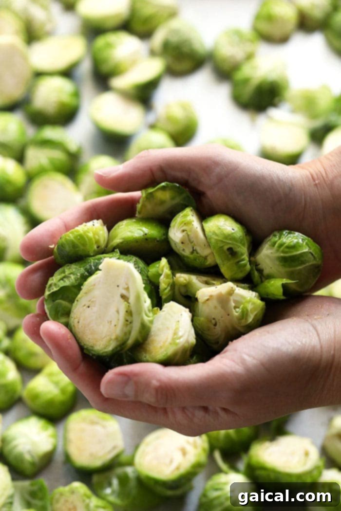 Roasted Brussels Sprouts with Crispy Bacon 3 Close-up of hands holding a pile of trimmed and halved Brussels sprouts.