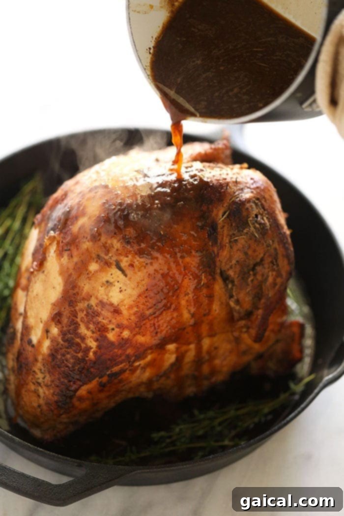 This sous vide turkey is the most tender and delicious turkey you will ever taste! If you're looking for a turkey recipe that you can prepare before Thanksgiving day or friends giving, then this sous vide turkey is for you! A chef's hand gracefully pours a rich, savory white wine sauce over a beautifully roasted sous vide turkey breast, creating a luscious sheen and enhancing its flavor, ready to be served.