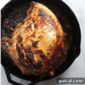 Flawless Festive Turkey 7 Sous Vide turkey cooked in a cast iron skillet, showcasing its golden-brown, crispy skin achieved through initial searing.