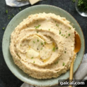 Velvety Cauliflower Mash 6 A bowl of creamy cauliflower mashed potatoes topped with butter and fresh herbs.