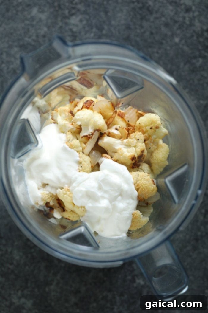Make these cauliflower mashed potatoes for your next dinner party! They make a great low carb side dish for the holidays! Not only are they healthy, but they are insanely delicious! All the roasted ingredients for cauliflower mash, along with dairy and broth, in a high-speed blender.