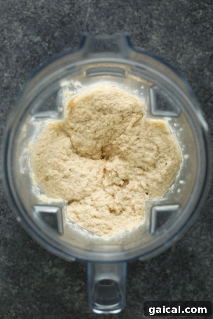 Make these cauliflower mashed potatoes for your next dinner party! They make a great low carb side dish for the holidays! Not only are they healthy, but they are insanely delicious! Blended cauliflower mash in a high-speed blender, showcasing its smooth texture.
