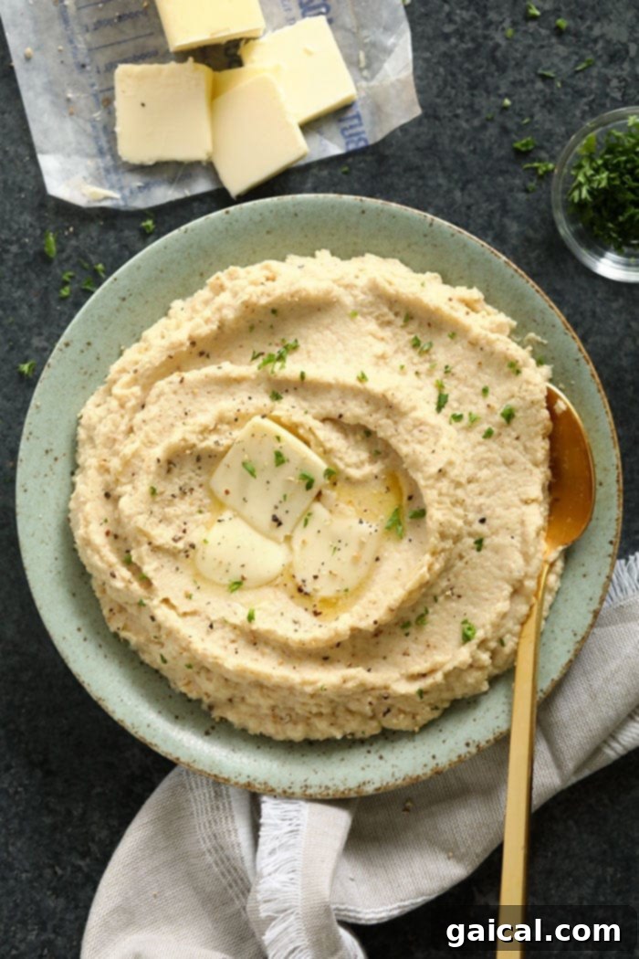 Make these cauliflower mashed potatoes for your next dinner party! They make a great low carb side dish for the holidays! Not only are they healthy, but they are insanely delicious! A bowl of cauliflower mash, garnished with fresh herbs and a pat of butter, ready to be served.