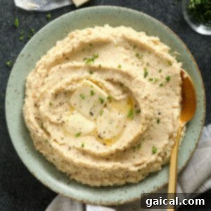 A bowl of creamy cauliflower mash, garnished with herbs.