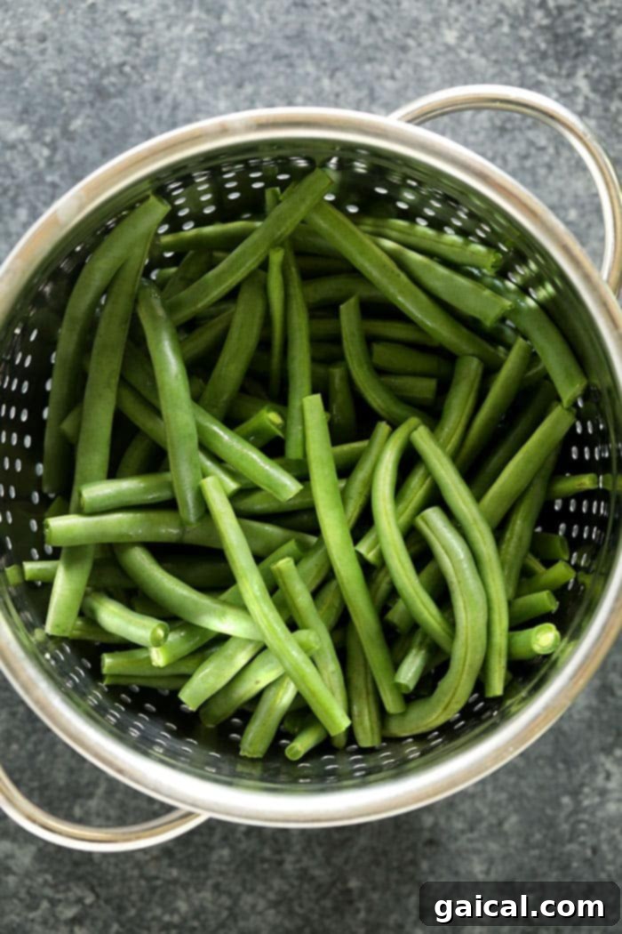 Green Beans with Toasted Almonds 3 Fresh green beans after blanching, glistening in a strainer, ready for the next step of the almondine recipe.