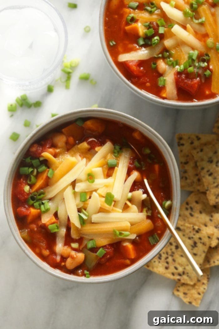 Delicious vegetarian chili in a bowl topped with shredded cheese and fresh green onions, ready to be enjoyed.
