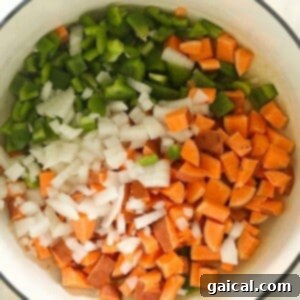 Onions, bell peppers, sweet potatoes, and jalapeños sautéing in a stockpot for vegetarian chili.