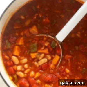 Vegetarian chili simmering in a pot on the stove, showing its rich texture before beans are added.