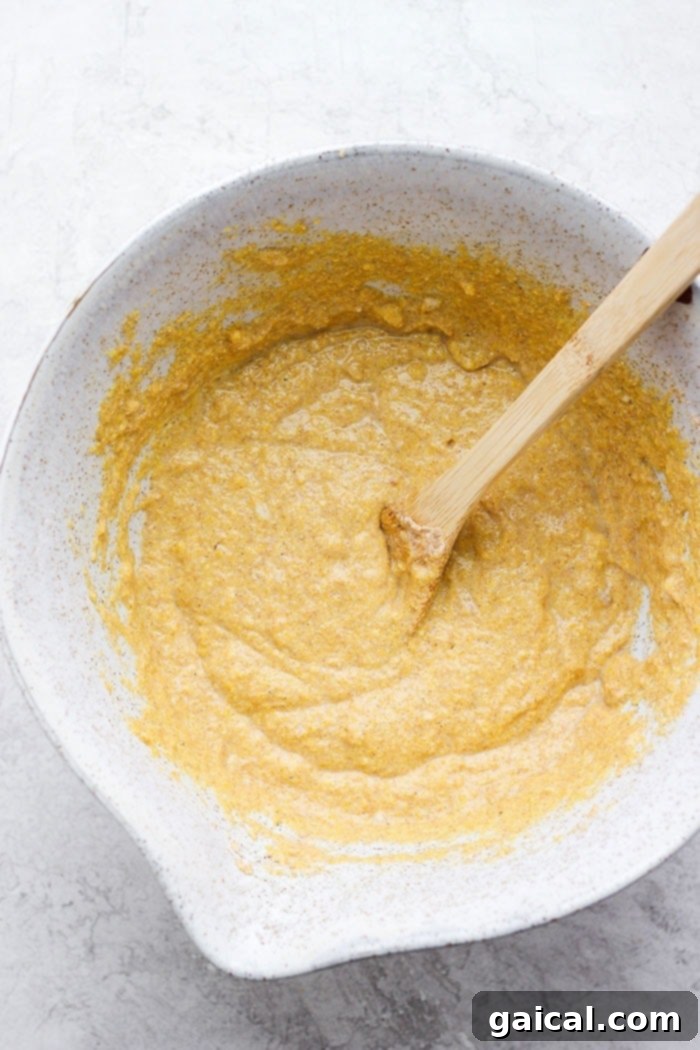 The most flavorful Skillet Cornbread made healthier with finely-ground cornmeal, white whole wheat flour, honey, and coconut oil. Close-up of cornbread batter with healthy ingredients in a mixing bowl, ready for baking.