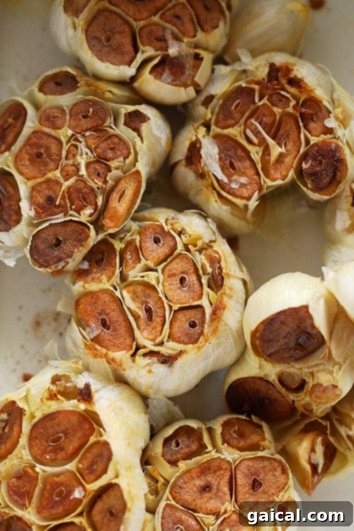 Learn how to roast garlic in the oven for a sweet, caramelized flavor that enhances any dish. Golden-brown roasted garlic cloves in a small baking dish, ready to be enjoyed.