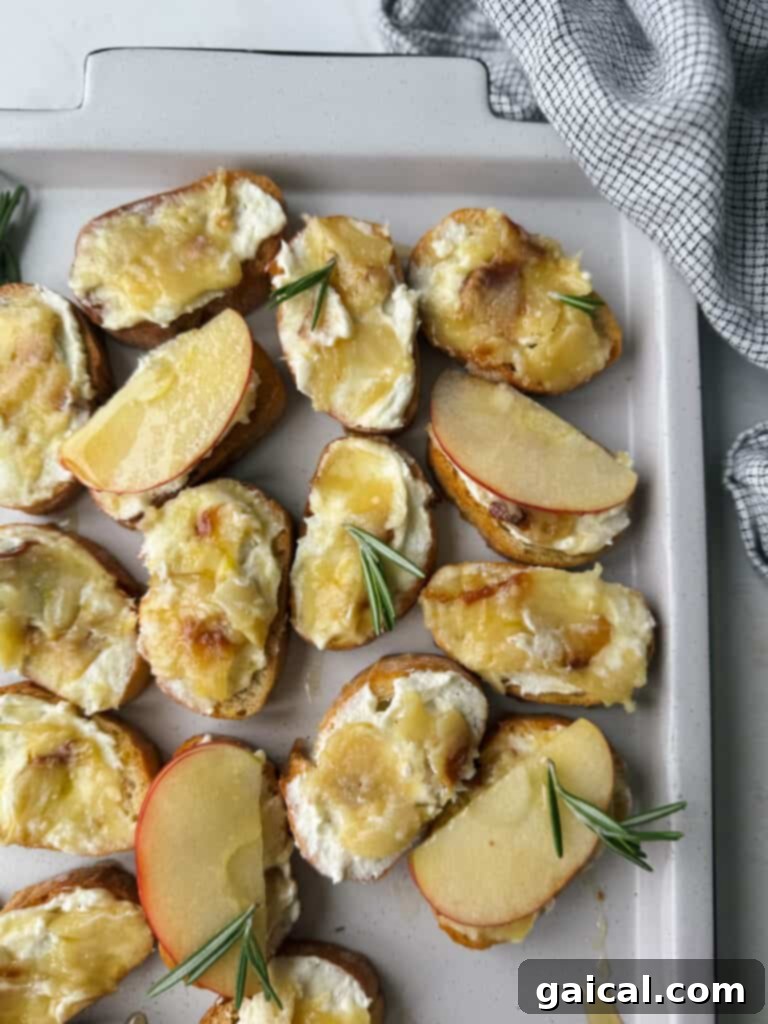 Perfect Roasted Garlic 2 Cheesy roasted apple and goat cheese potato wedges with rosemary sprigs on a baking sheet, perfectly complemented by the aroma of roasted garlic.