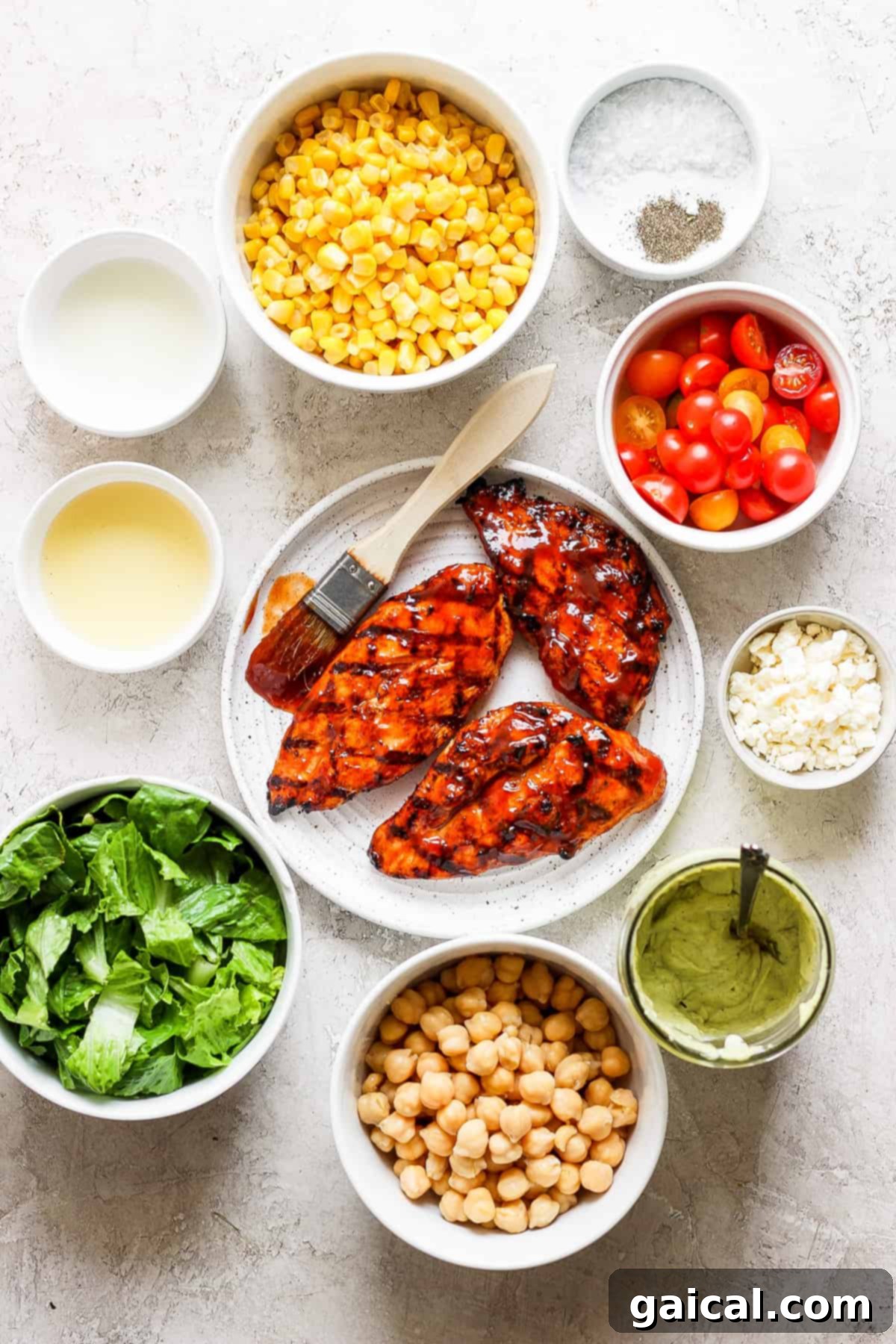 Grilled BBQ Chicken Salad 3 Various fresh ingredients for BBQ chicken salad laid out, including corn, garbanzo beans, tomatoes, and romaine.