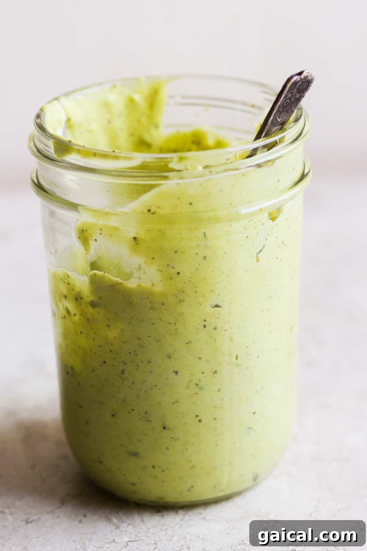 Grilled BBQ Chicken Salad 4 A jar filled with green avocado ranch dressing, with a spoon inside.