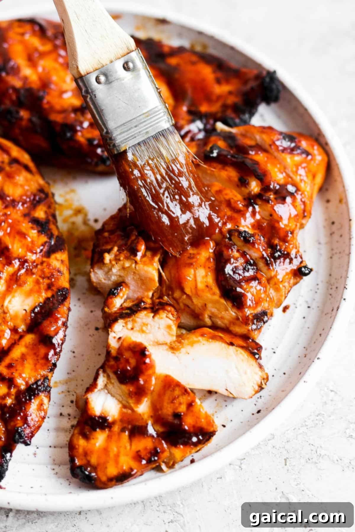 Grilled BBQ Chicken Salad 5 BBQ chicken breast on a plate with a basting brush, ready to be sliced.