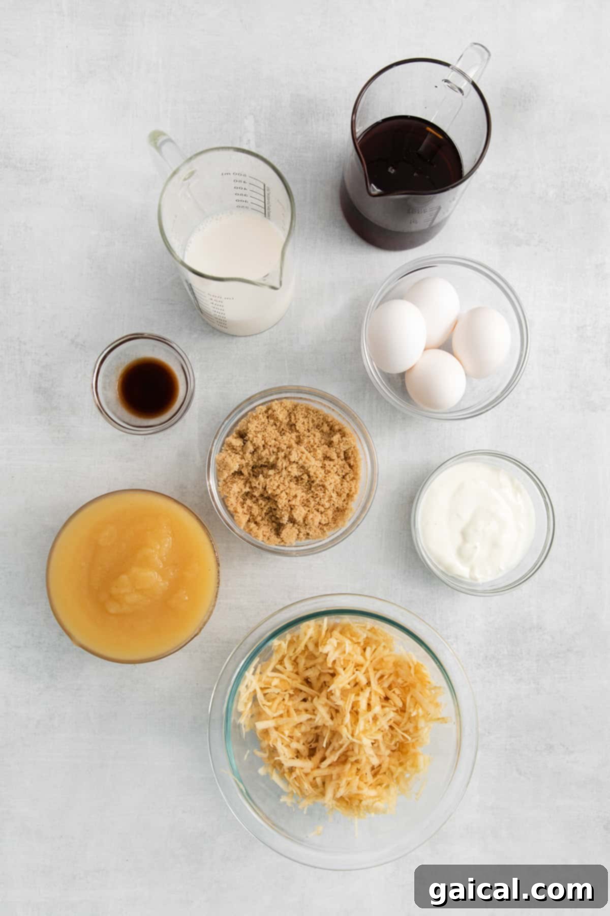 Assorted ingredients for an apple cake, including apples, applesauce, spices, and flour, arranged in small bowls.