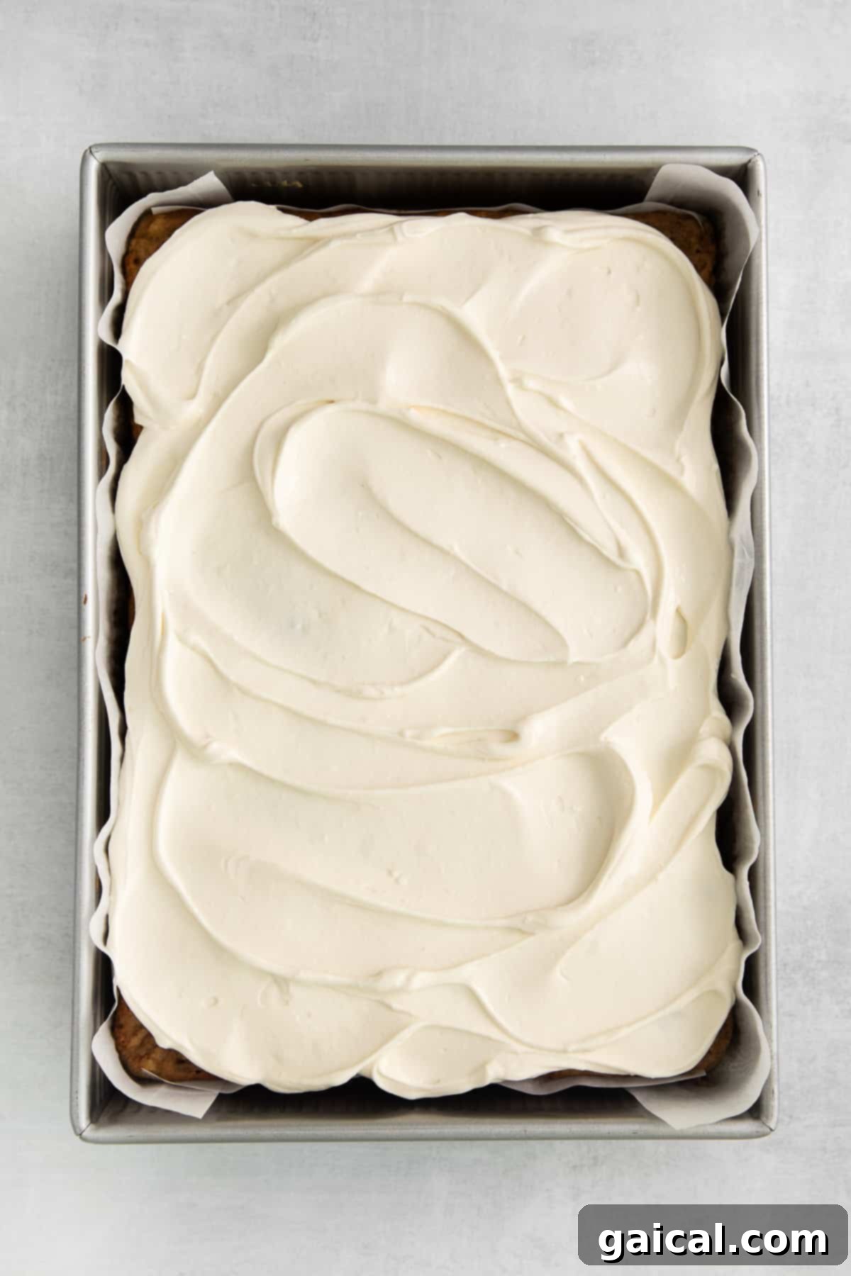 A perfectly frosted apple cake with cream cheese frosting, elegantly garnished with a light sprinkle of chai spice.