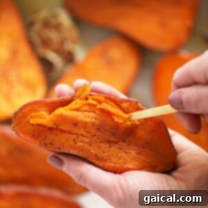 Sweet Potato Mash 5 A person using a spoon to scoop the soft sweet potato flesh from its skin into a bowl.