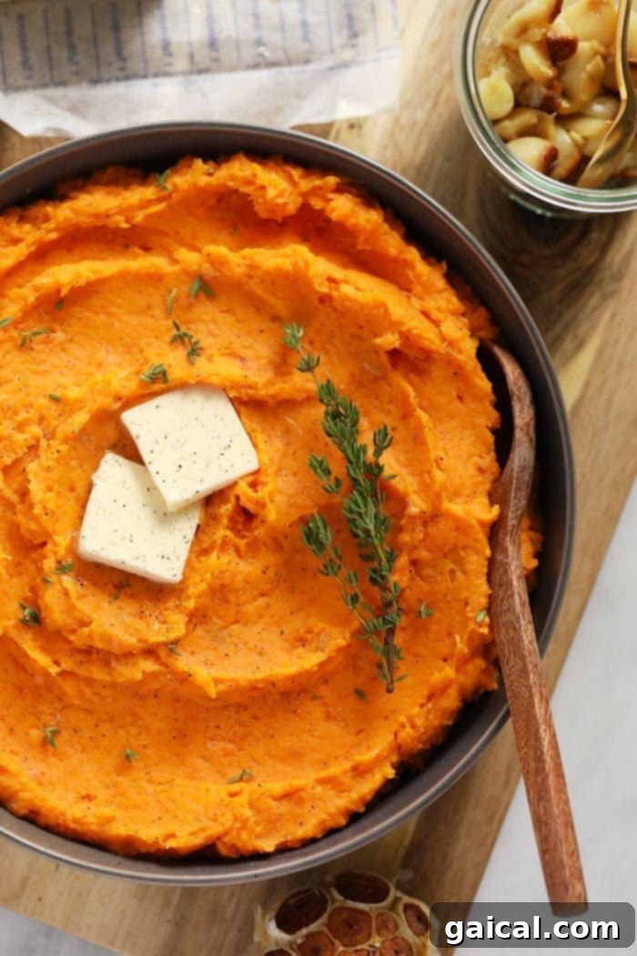 Serve these healthy mashed sweet potatoes at your next holiday gathering or make it as a side next to any of your favorite entrees. A serving bowl filled with creamy mashed sweet potatoes, garnished with a pat of melting butter and fresh thyme sprigs.