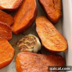 Sweet Potato Mash 4 Roasted sweet potatoes and garlic in a green baking dish, showing the skin-side up after flipping.