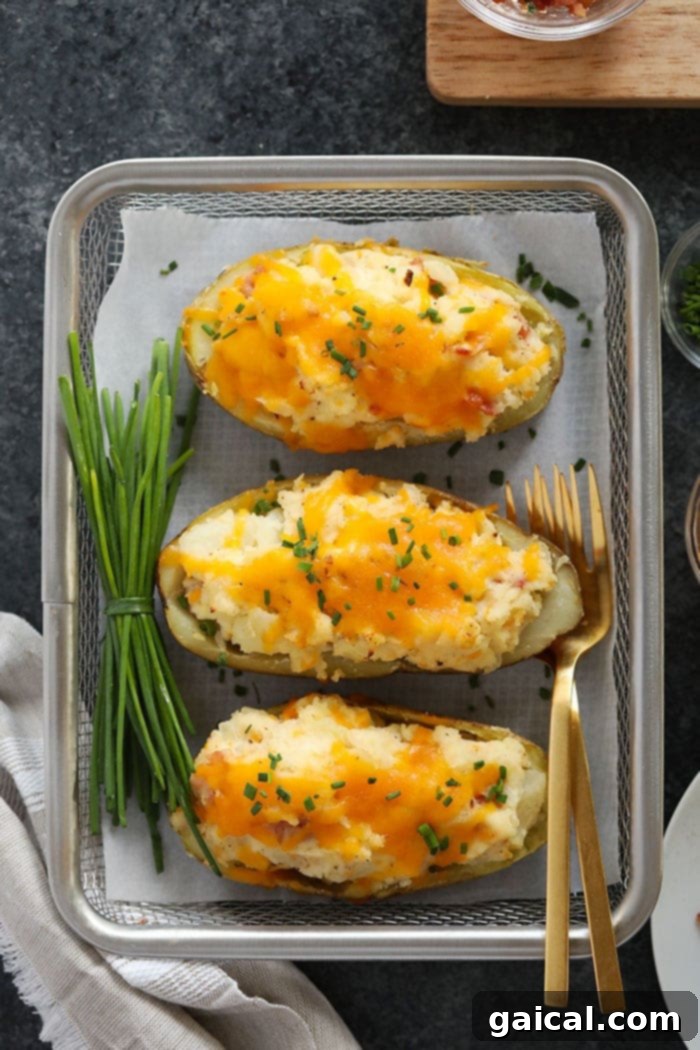The ultimate dinner or side dish: perfectly crispy and cheesy twice baked potatoes. Golden brown twice baked potatoes ready to be served, garnished with fresh herbs.
