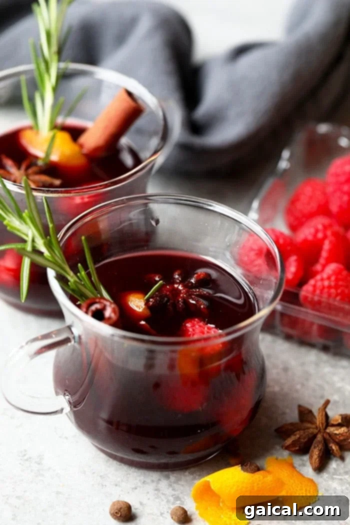 Spiced Raspberry Mulled Wine A festive mug of mulled wine, garnished with fresh rosemary and cranberries, exuding a warm holiday glow.