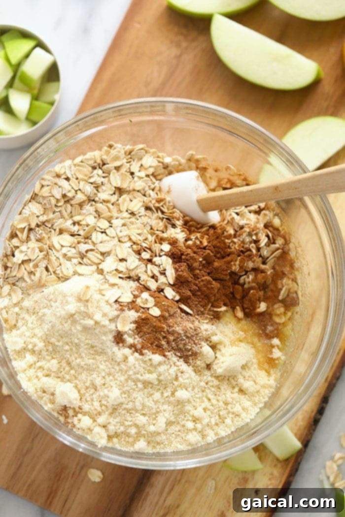 Prepared apple pie bar crust mixture in a mixing bowl, showing the crumbly texture of almond meal and oats, ready to be pressed into a pan.