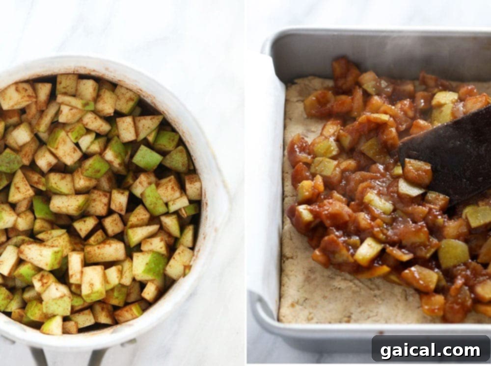 Warm, spiced apple filling being carefully poured into a baked sugar cookie crust in a square baking pan, ready for the crumble topping.