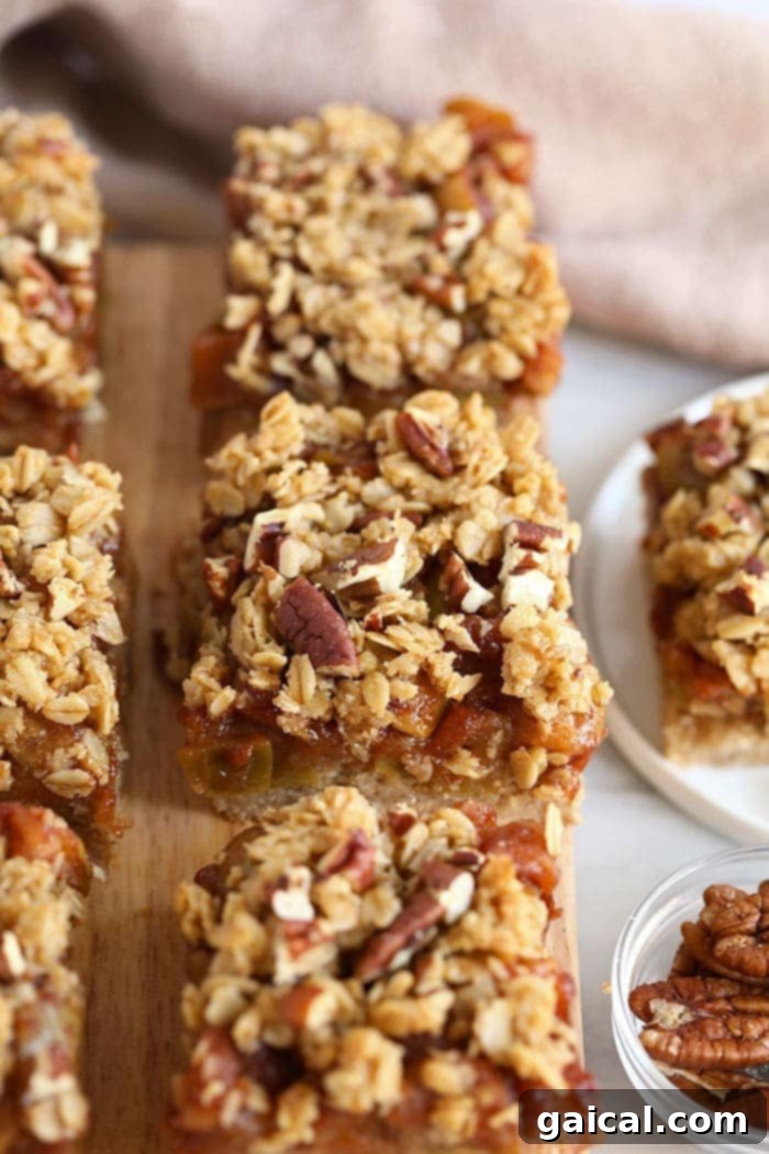 Gluten-free apple crumble bars, beautifully topped with a rustic oat and pecan crumble, presented on a wooden board ready to be served.
