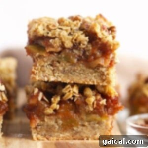 Stacked apple pie bars with green apple filling, buttery crust, and crumble topping, ready for serving.