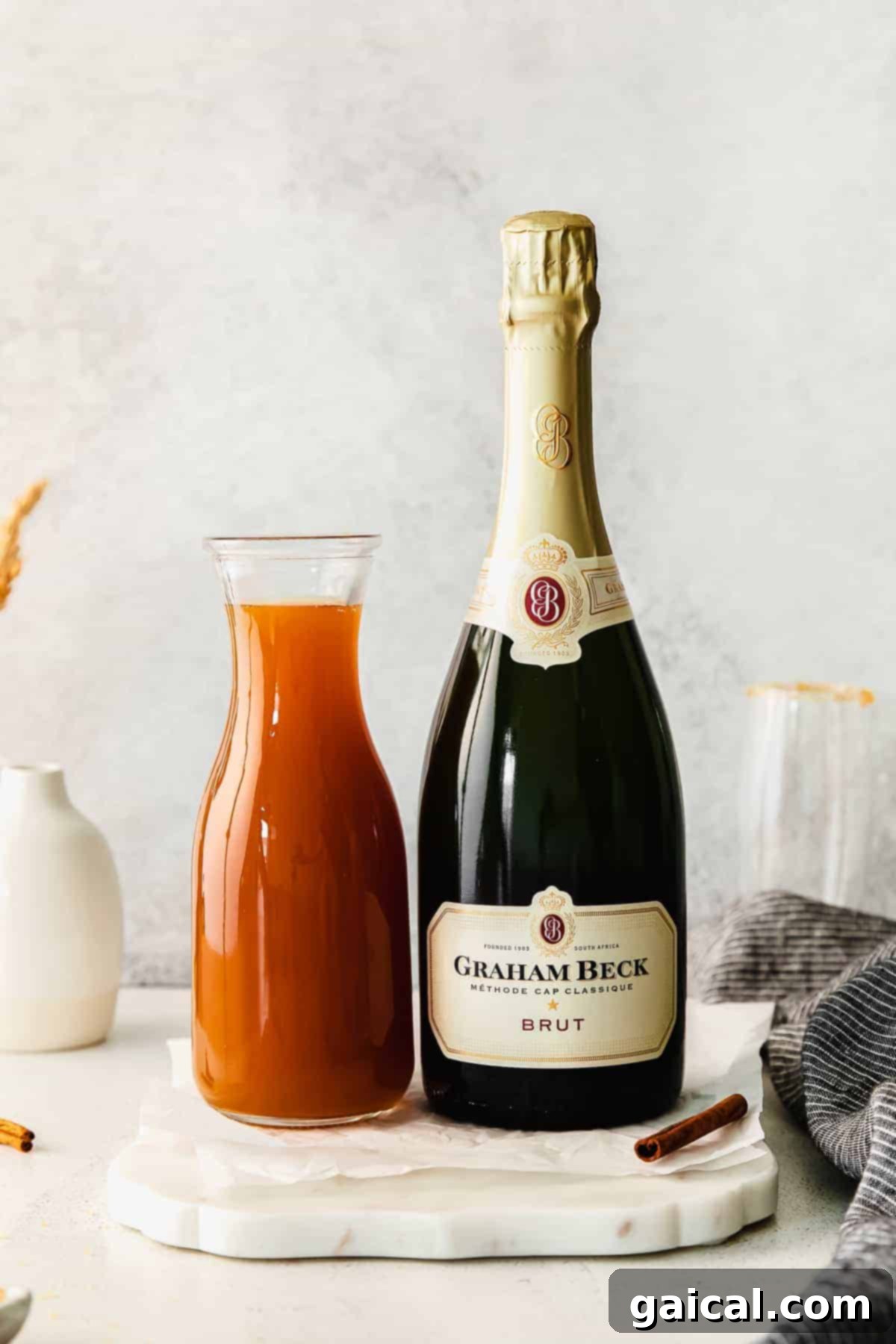 Spiced Apple Mimosa 3 Two separate glasses, one filled with golden apple cider and the other with clear, bubbly champagne, illustrating the two main ingredients of the mimosa.