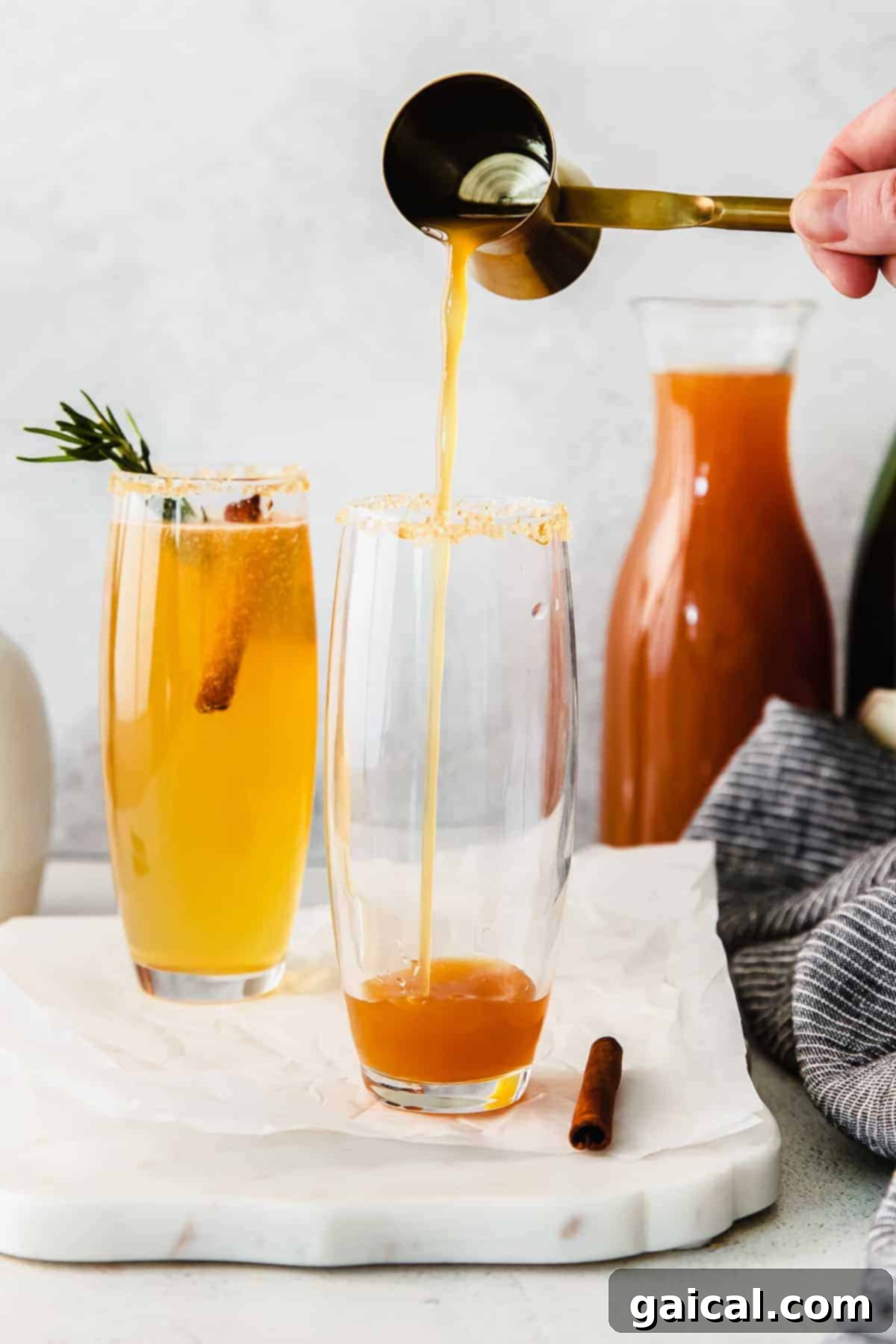 Spiced Apple Mimosa 5 A person carefully pouring golden apple cider into a champagne flute, preparing the base for an apple cider mimosa.
