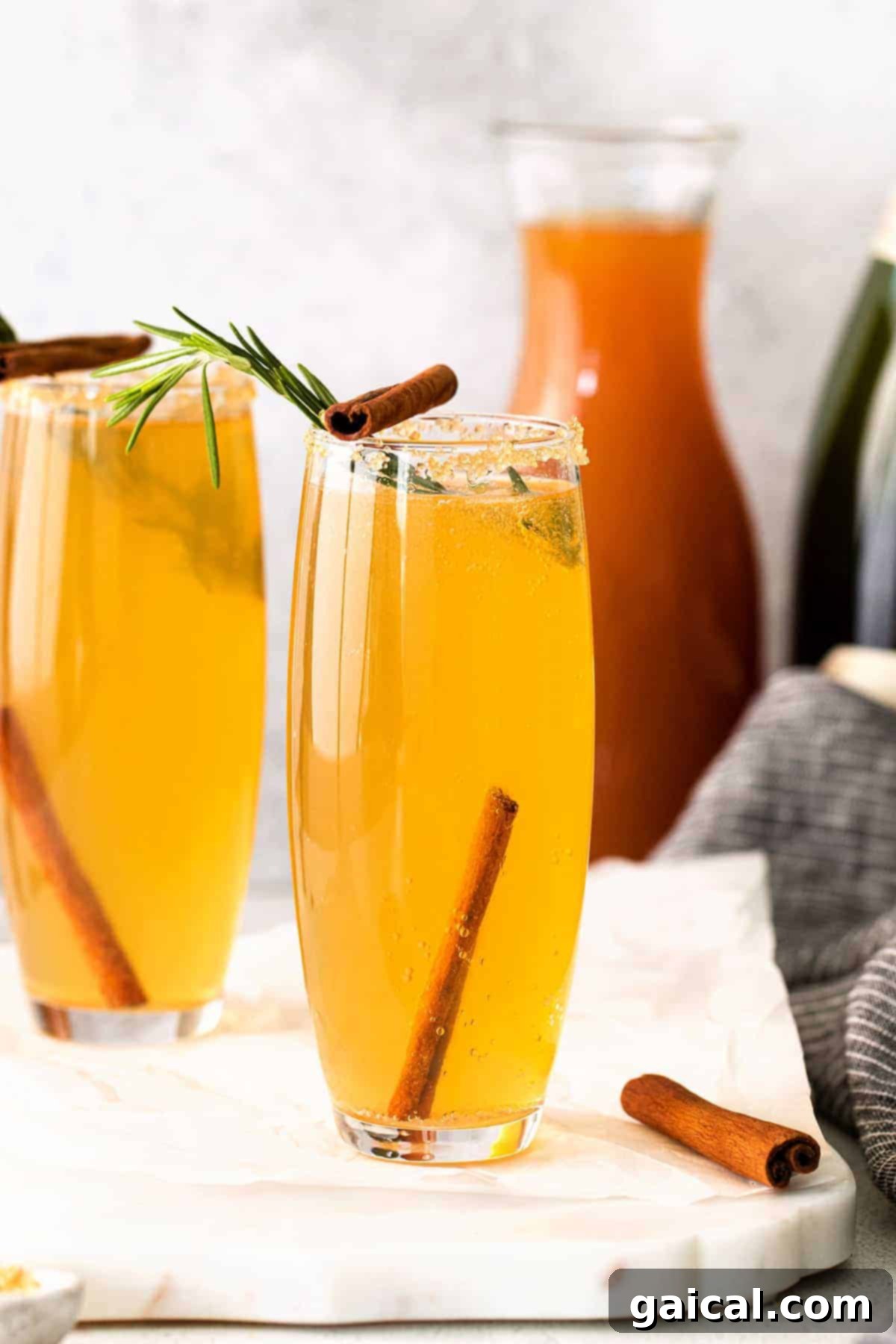 Spiced Apple Mimosa 8 Two beautifully prepared apple cider mimosas, garnished with cinnamon sticks and fresh apple slices, ready for serving.