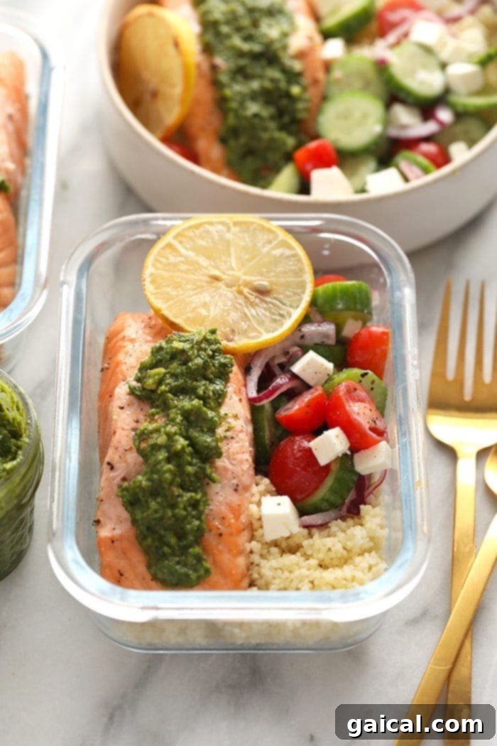 Effortless Mediterranean Salmon Meals 2 Beautifully arranged Mediterranean Salmon Meal Prep in a clear glass container, showcasing a flaky salmon fillet topped with vibrant green pesto, a colorful Greek salad, and fluffy couscous