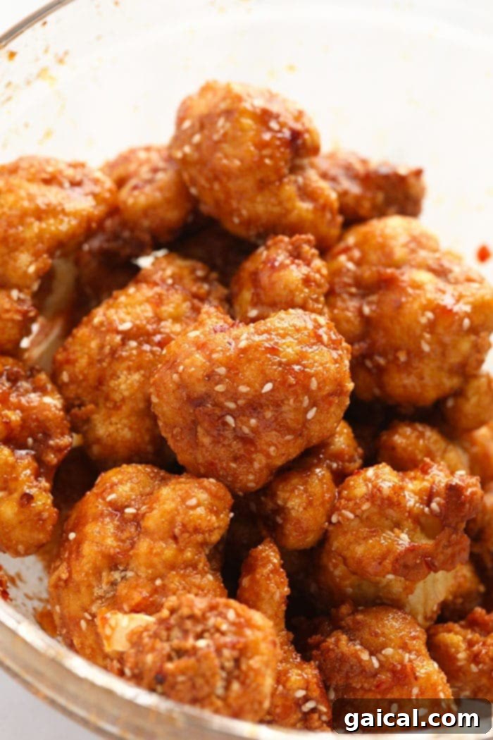 Crispy General Tso's Cauliflower 5 General Tso's Cauliflower being tossed in a glass bowl with sauce