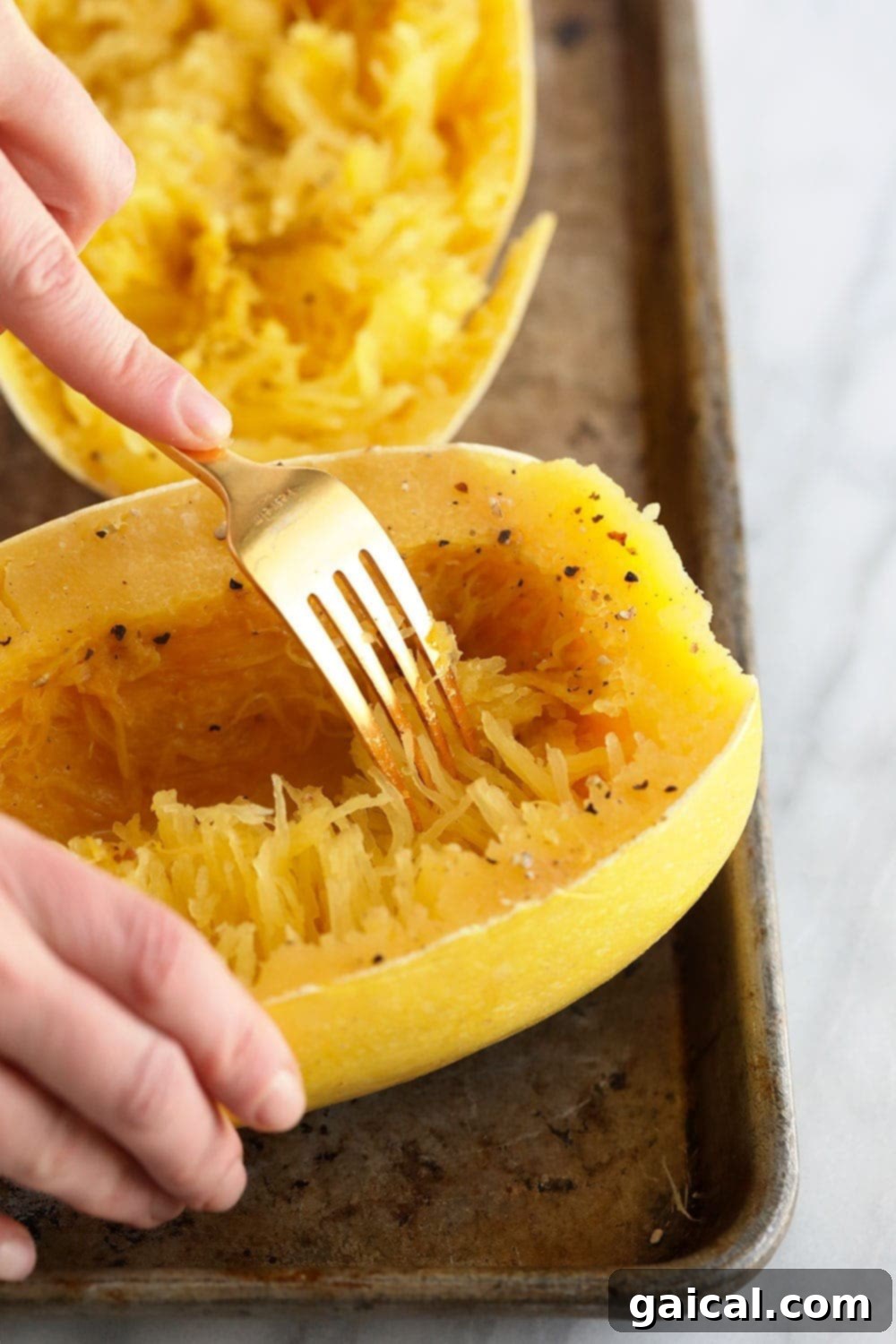 Shredding cooked spaghetti squash into noodle-like strands with two forks