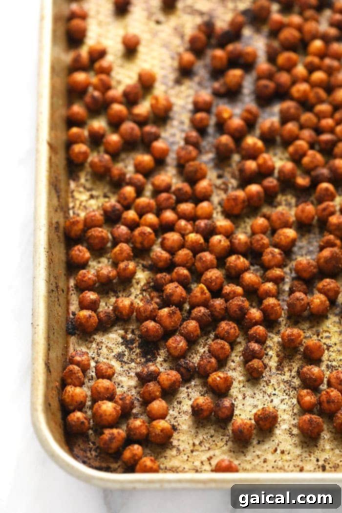 Close-up of perfectly crispy, golden-brown chickpeas seasoned with Moroccan spices, spread on a baking sheet.