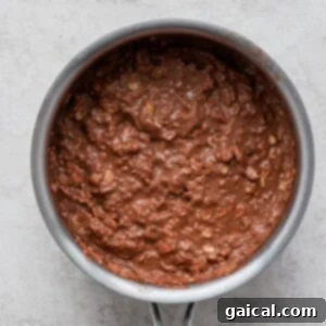 Decadent Chocolate Protein Oatmeal 4 Chocolate batter in a pan on a white surface, made with protein oatmeal, simmering to perfection.