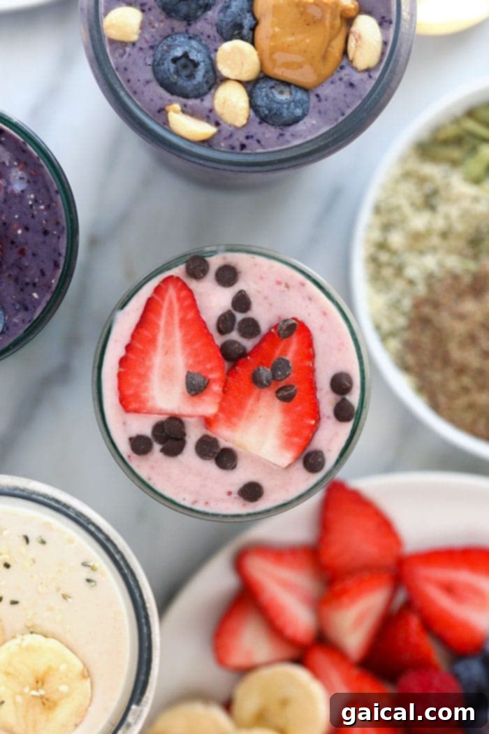 A vibrant pink strawberry protein shake in a tall glass, garnished with fresh strawberries.