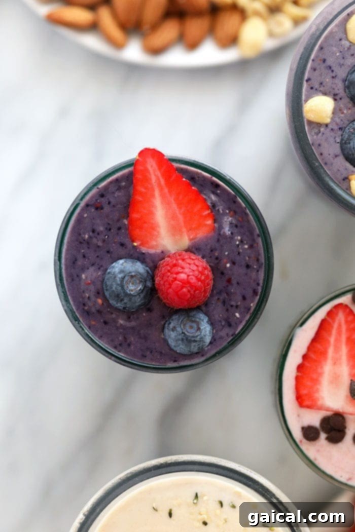 A vibrant purple triple berry protein shake in a glass, topped with fresh berries.