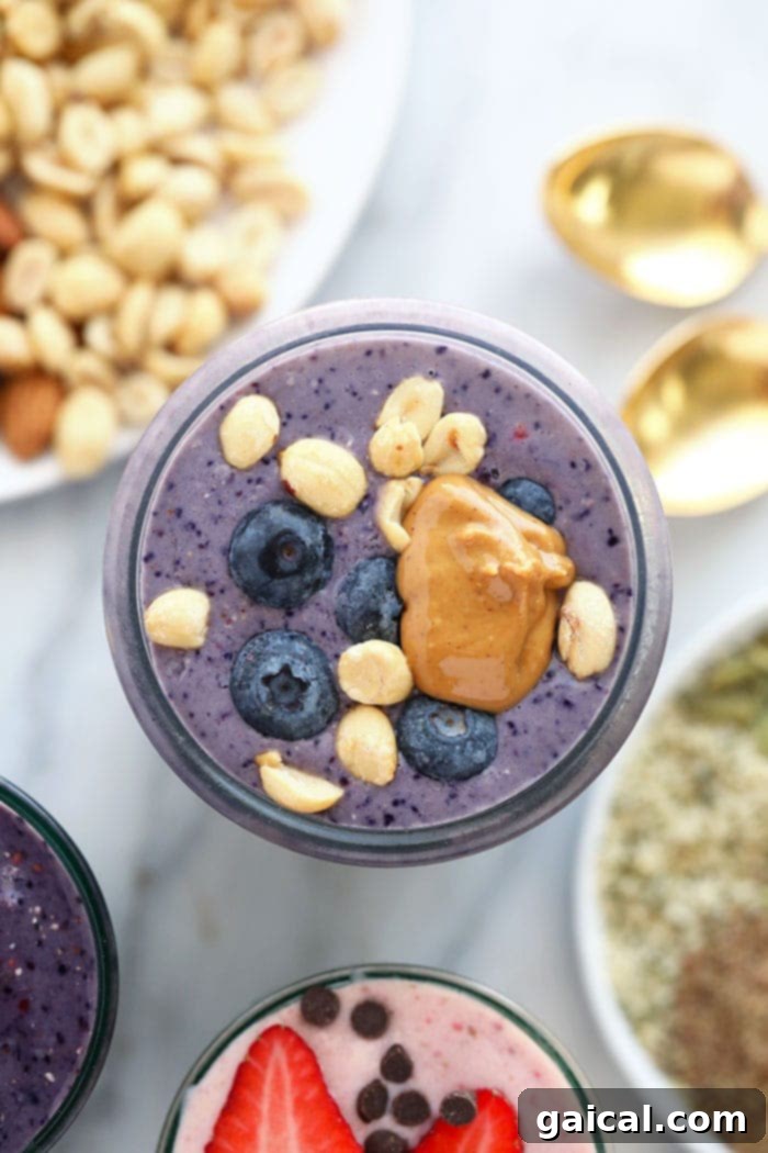 A creamy peanut butter and jelly protein shake in a glass with a spoon, showing layers of color.