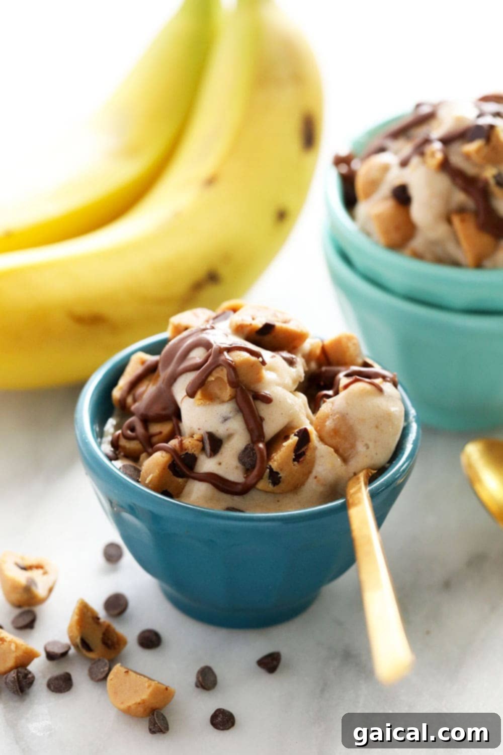 Cookie Dough Banana Bliss 2 A beautiful bowl of vegan cookie dough banana nice cream, garnished with extra cookie dough chunks and a drizzle of chocolate sauce, ready to be enjoyed.