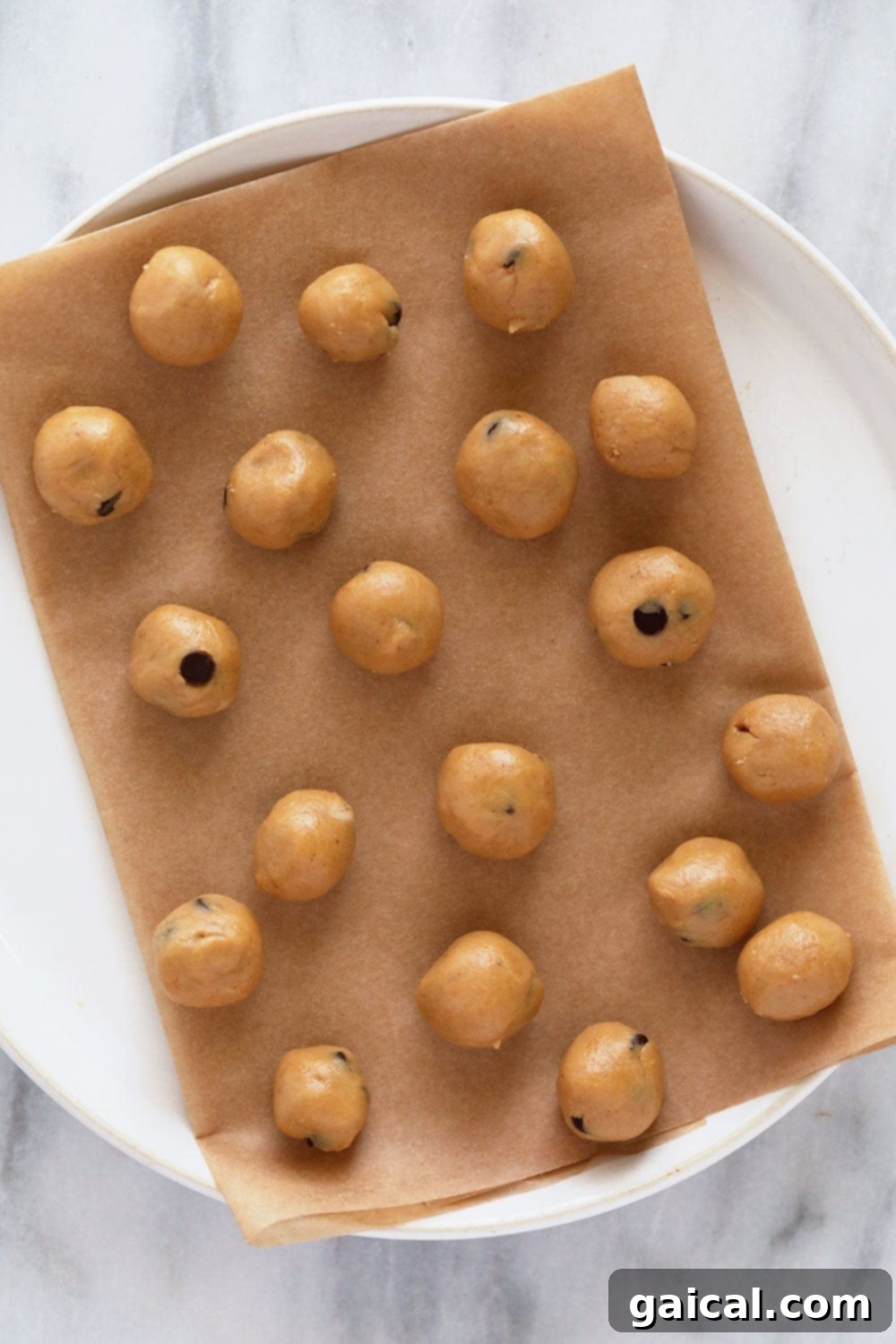 Cookie Dough Banana Bliss 3 Small, perfectly rolled balls of edible cookie dough, speckled with mini chocolate chips, resting on a white plate, ready for freezing.