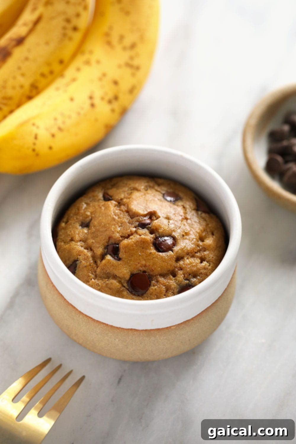 Freshly baked banana mug cake in a mug, topped with melted chocolate chips, ready to be enjoyed.