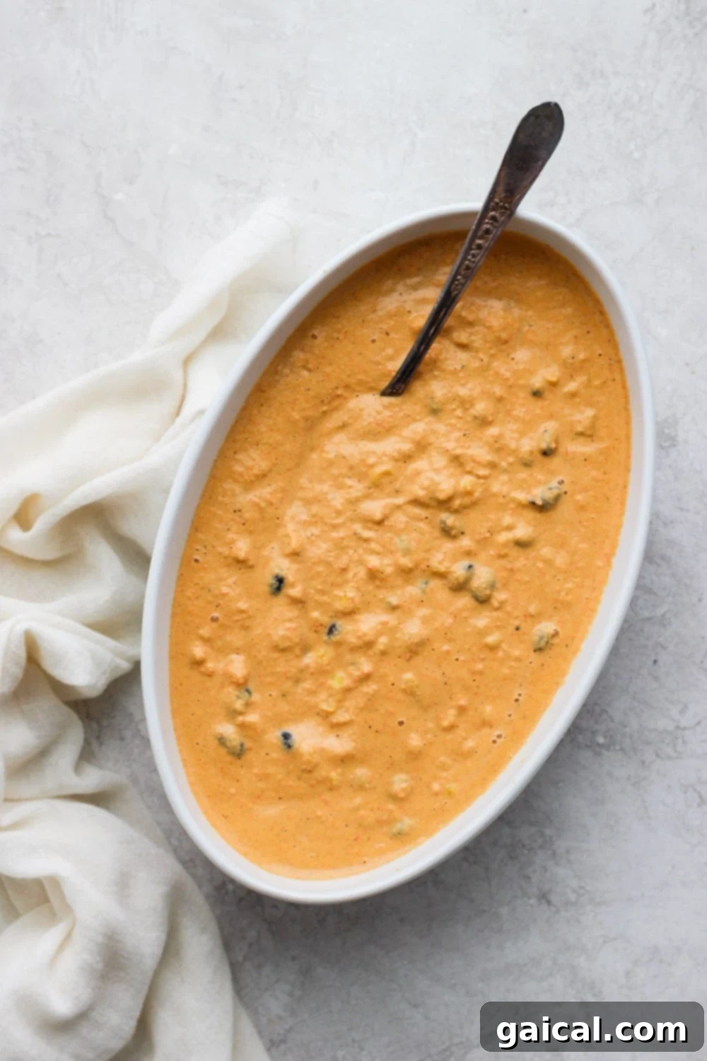 A close-up shot of Vegan Mexican Street Corn Queso Dip in a rustic serving bowl, garnished with fresh cilantro, with a spoon ready for serving.